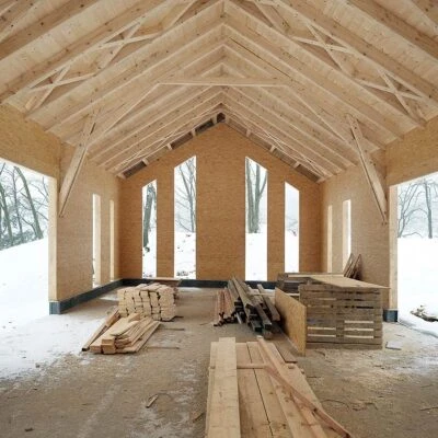 Nezhotovená dřevěná stodola s viditelnými trámy a stavebními materiály.