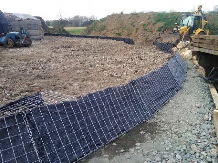 Černá geotextilie je položena na staveništi s těžkou technikou.