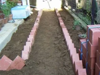 Řada červených cihel sloužících jako okraj pro zahradní postel.
