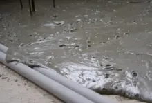 Čerstvý beton se rozlévá po povrchu s viditelnými bublinami.