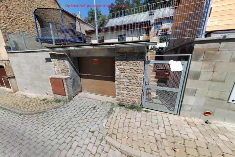 Opěrná zeď po rekonstrukci s vchodem do garáže a plotem.