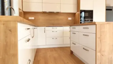 Moderní kuchyň s bílými skříněmi a dřevěnými pracovními deskami.