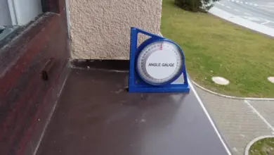 Modrý úhlový měřič na starém dřevěném parapetu u okna.