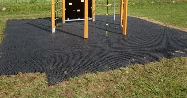 Černý bezpečnostní povrch z modulů pod dětským hřištěm.