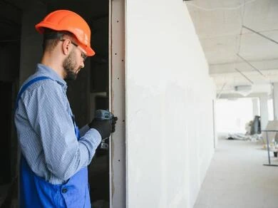 Stavebník měří rámeček sádrokartonové příčky na stavbě.