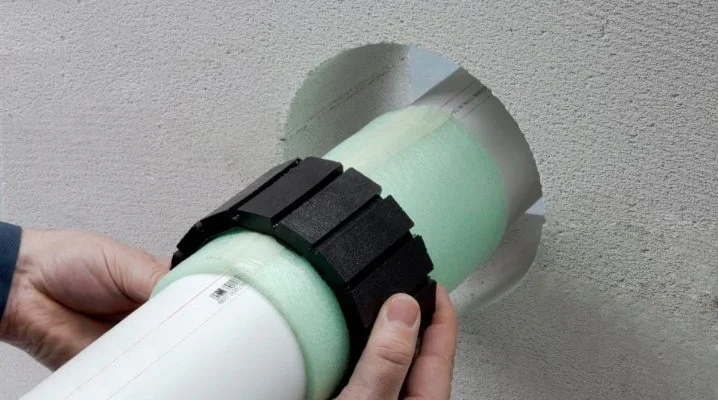 Instalace izolovaného potrubí do stěny s použitím černých svorek.