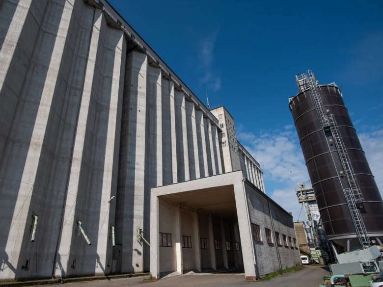 Velké obilní skladovací zařízení s betonovým sílem a kovovou nádrží.