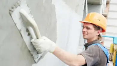 Stavebník nanáší omítku na stěnu pomocí špachtle.