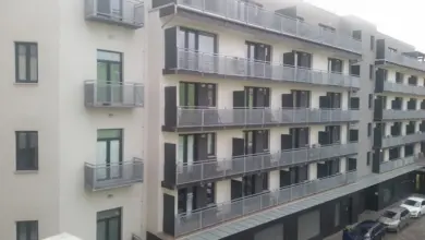 Moderní bytový dům s balkony a velkými okny.