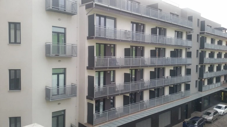 Moderní bytový dům s balkony a velkými okny.