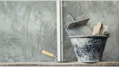 Nástroje pro omítku v kovovém koši na dřevěné desce.