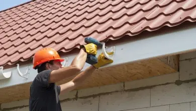 Montáž okapových háků pomocí vrtáku pod střechou.