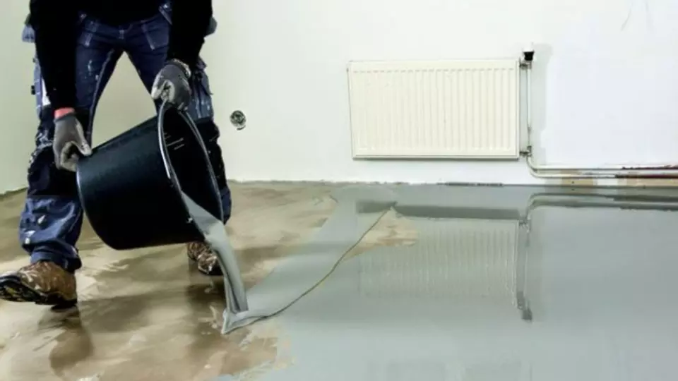 Pracovník nalévá samonivelační směs na podlahu.