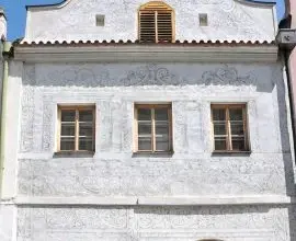 Historická budova se vykrabovanými vzory na fasádě technikou sgrafit.