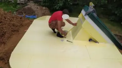 Muž sestavuje žlutý poklop do sklepa venku.