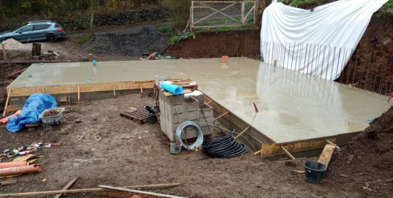 Zalévání betonu pro základovou desku na svahu.