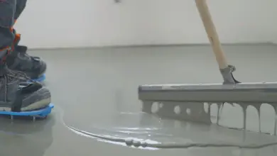 Pracovník rozhlazuje samonivelační podlahu hladkou špachtlí.