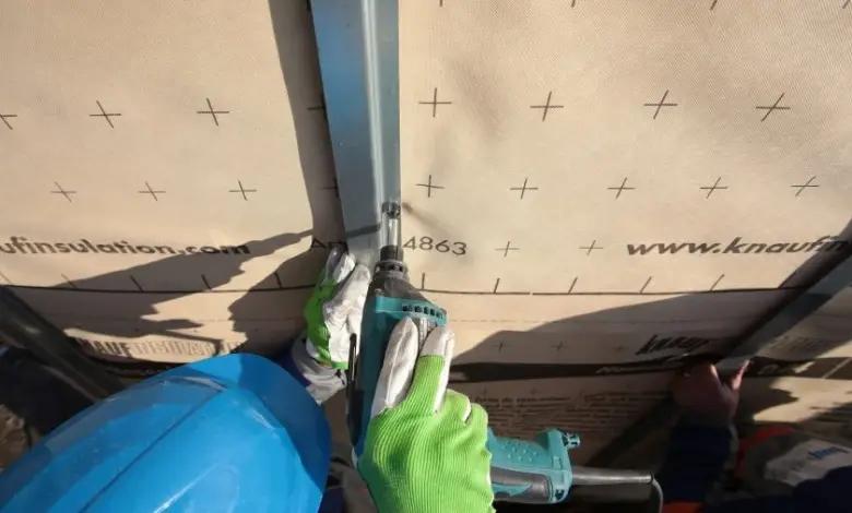Montáž větrané fasády: ruční montáž izolačních desek s elektrickým vrtákem.
