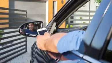 Muž fotí sebe v zrcátku auta u brány