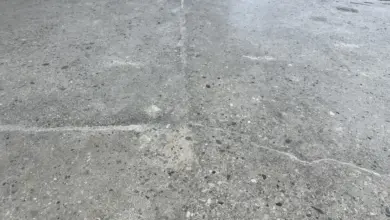 Překrytá betonová plocha s viditelnými trhlinami a prasklinami.