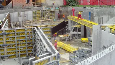 Staveniště s pracujícími dělníky a betonovými tvary.