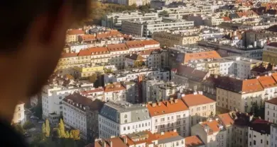 Pohled na město s červenými střechami z okna.