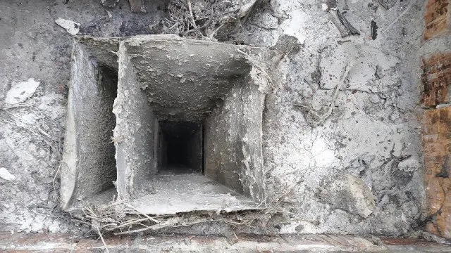 Větrací šachta v zdi panelového domu s viditelným otvorem dovnitř.