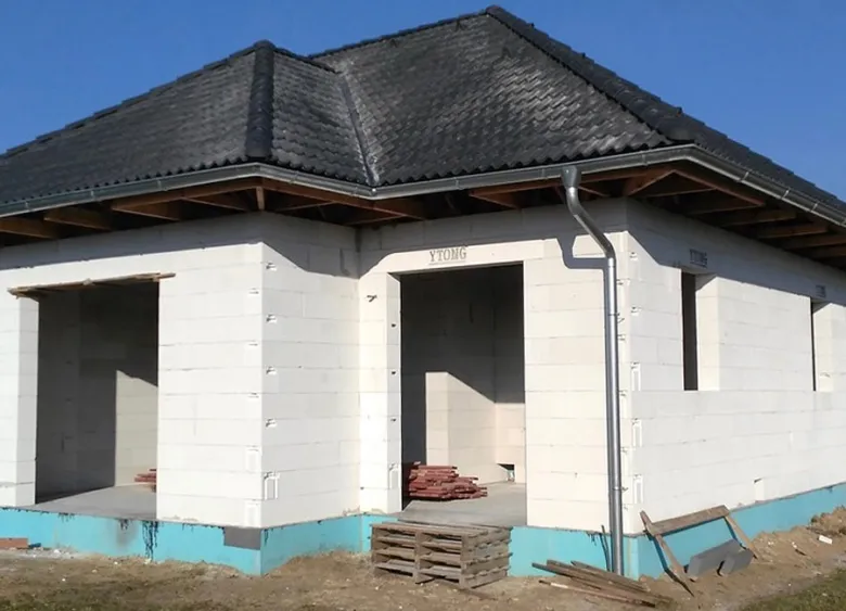 Stavba domu z plynosilikátových bloků s tmavou střechou.