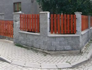 Nově postavený zděný plot s dřevěnými prkny na ulici.