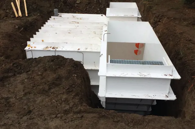 Bílá modulární konstrukce sklepa nebo suterénu v zemi při stavbě.