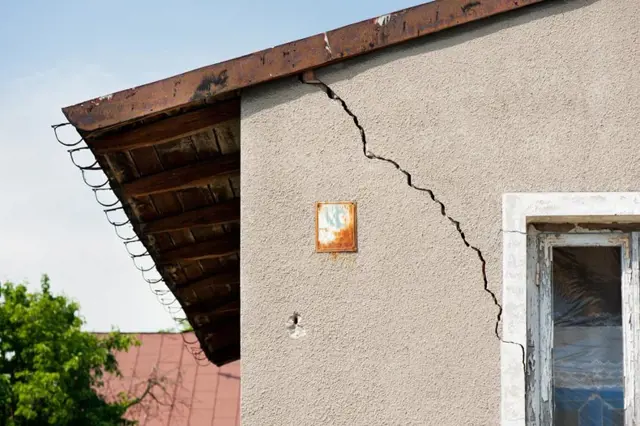 Velká prasklina na fasádě domu u okna.