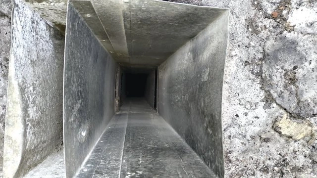 Vnitřní pohled do betonové větrací šachty v panelovém domě.