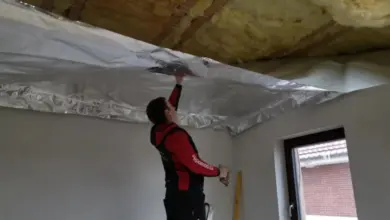 Montáž parotěsné fólie na stropní izolaci v interiéru.