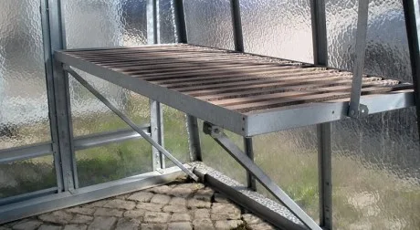 Dřevěná podlaha pro průchod ve skleníku s kovovým rámem.