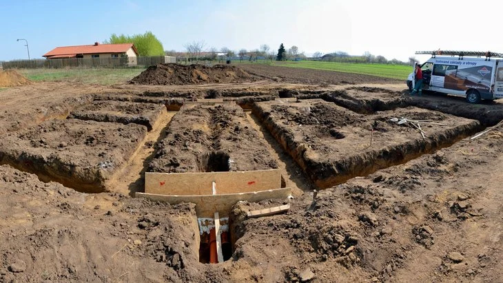 Zasazený základ domu s vykopanými jámy pro pásovou nebo deskovou konstrukci.