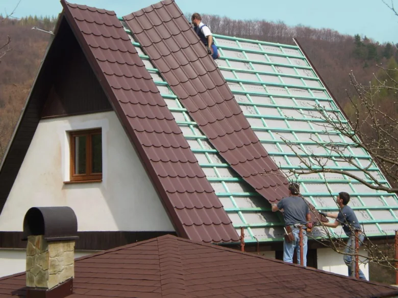Práce na střechě: montáž nových tašek místo plechové krytiny.