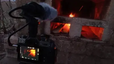 Kamera natáčí dovnitř kamenné pece s hořícím ohněm.