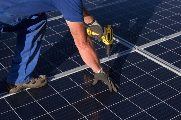 Montáž fotovoltaických panelů na plochou střechu pomocí kovových nosníků.