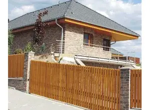 Moderní dům s kamennou fasádou a dřevěným plotem.