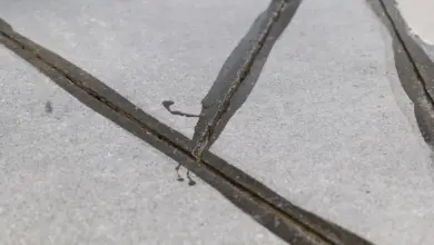 Blízký záběr na povrch světlého betonu s tmavými spárami mezi deskami.