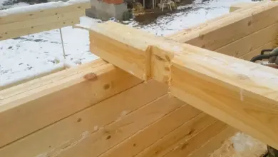 Dřevěný trám připevněn k cihlové zdi v zimním prostředí.