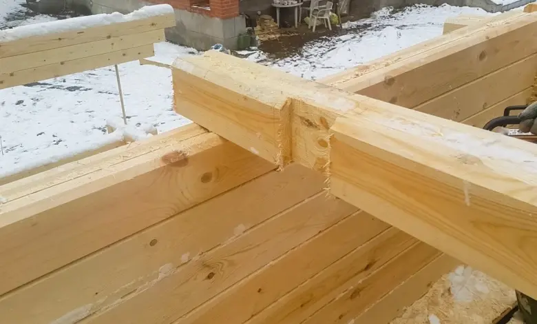 Dřevěný trám připevněn k cihlové zdi v zimním prostředí.