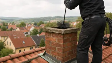 Člověk čistí komín na střeše štětcem.