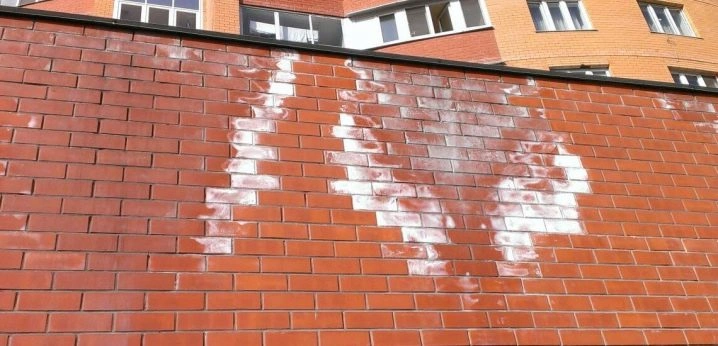 Bílý výkvět na červené cihlové zdi po vodě.