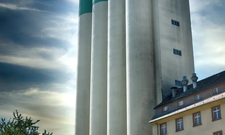 Vysoká obilní silo s zelenými pruhy na pozadí modrého nebe.
