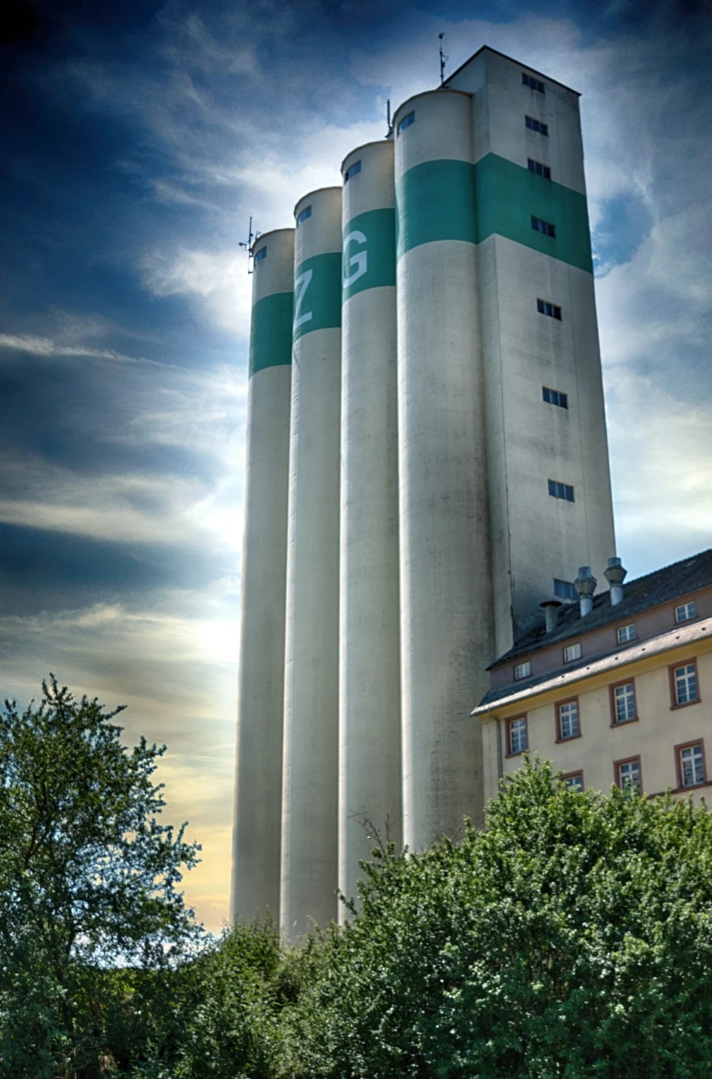 Vysoká obilní silo s zelenými pruhy na pozadí modrého nebe.