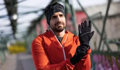 Muž v sportovním oblečení ukazuje rukavice venku.