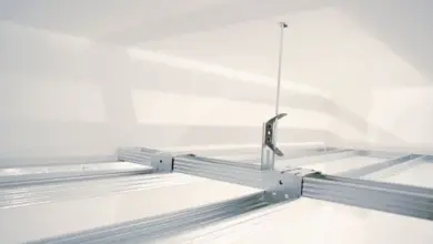 Bílá rastrová konstrukce pro podhled s kovovým úpravovacím mechanismem.