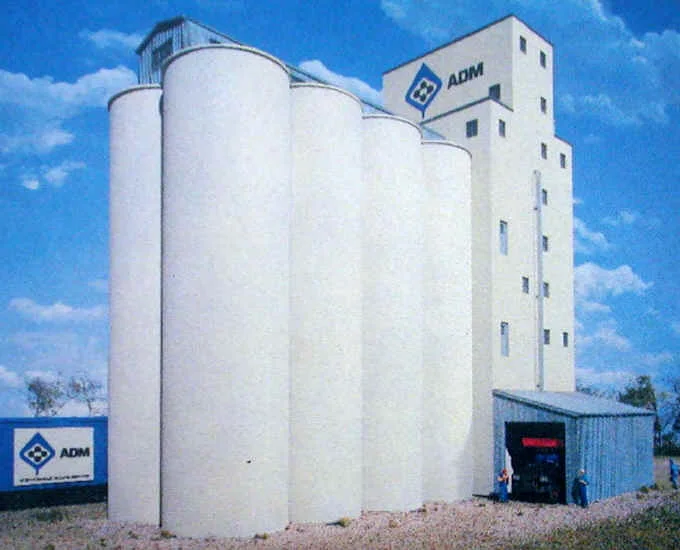 Velké obilné silo s nádrží značky ADM pod modrou oblohou.
