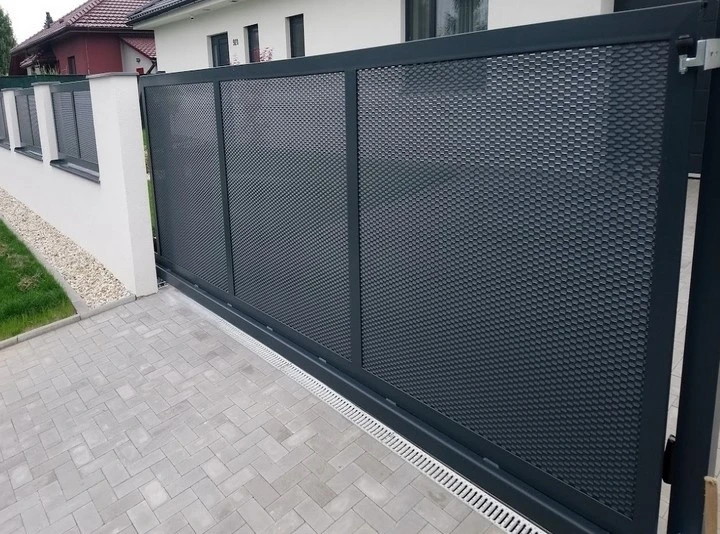 Moderní brána s mřížkou pro vjezd na pozemek.